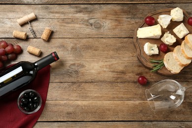 Flat lay composition with red wine and snacks on wooden table, space for text