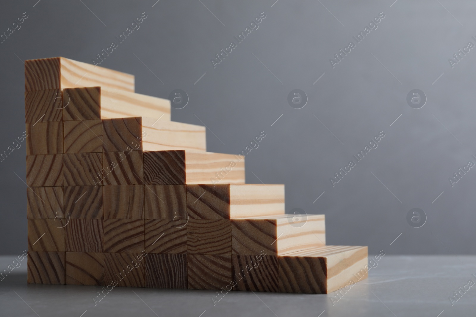 Photo of Steps made with wooden blocks on table against grey background, space for text. Career ladder