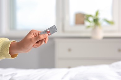 Photo of Woman holding blister of emergency contraception pills in bedroom, closeup. Space for text