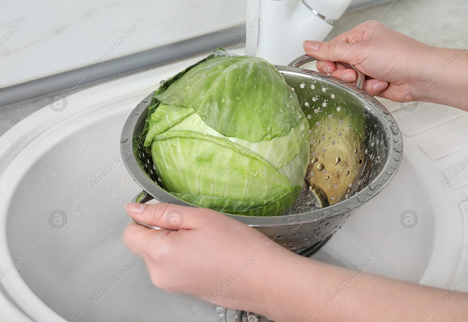 Photo of Woman washing fresh cabbage in colander under water, closeup