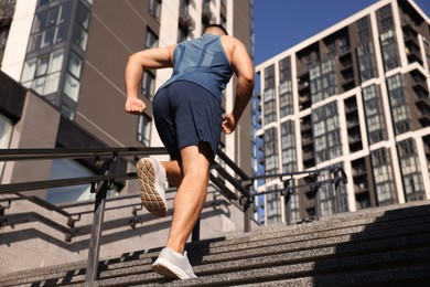 Man running up stairs outdoors on sunny day, low angle view