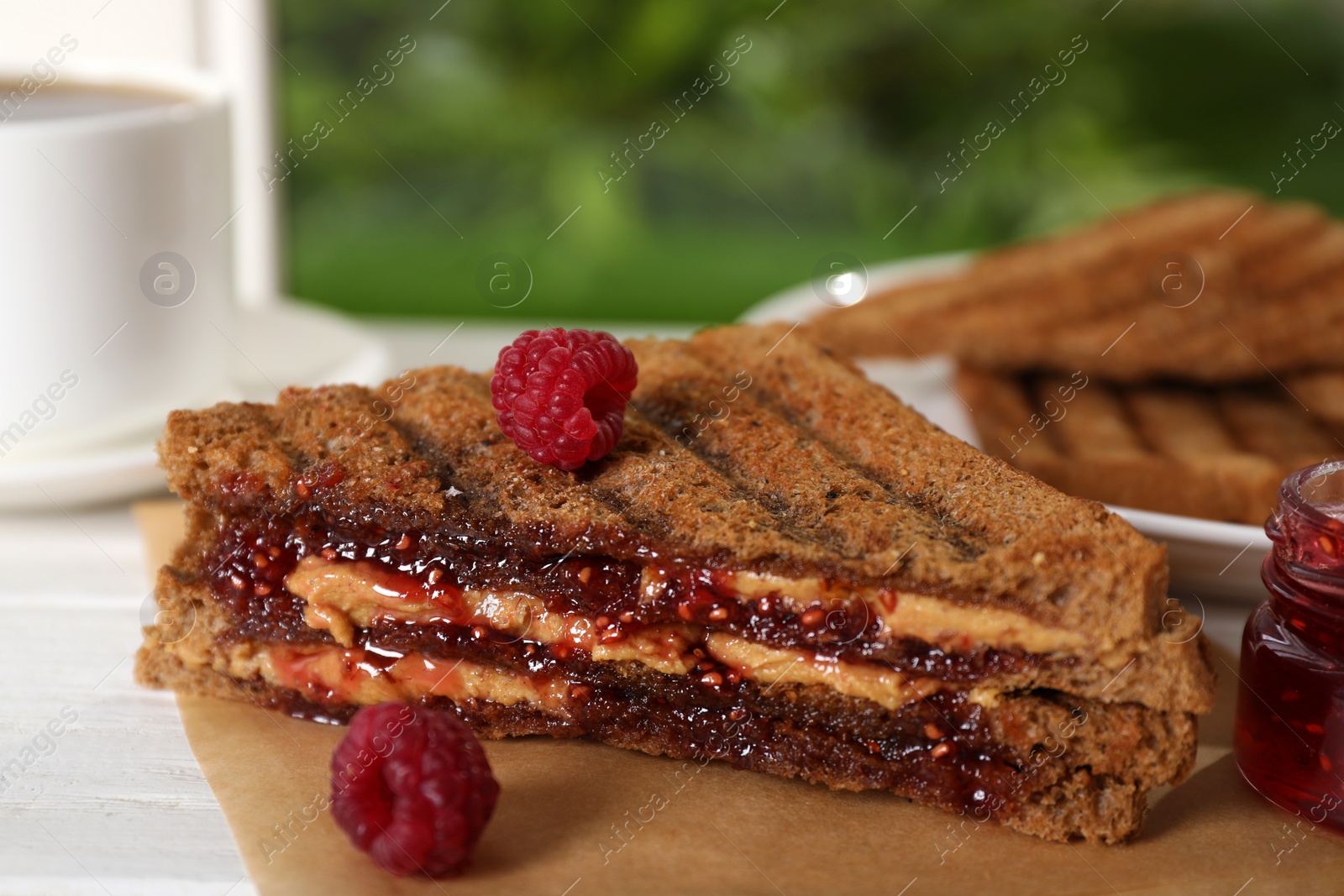Image of Tasty sandwich with raspberry jam and peanut butter for breakfast on table, closeup