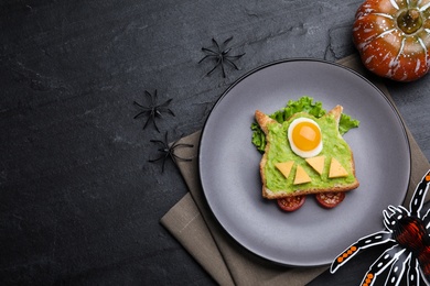 Photo of Halloween themed breakfast served on black table, flat lay and space for text. Tasty sandwich with fried egg
