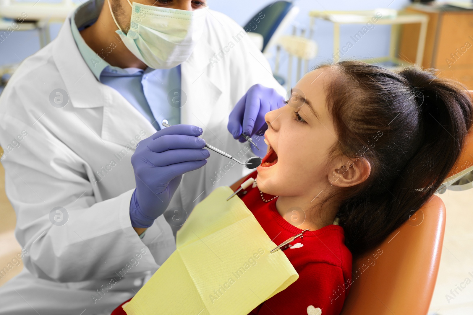 Photo of Professional dentist working with little patient in modern clinic