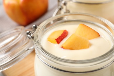 Photo of Delicious yogurt with fresh peach in glass jar, closeup