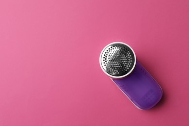 Modern fabric shaver on pink background, top view. Space for text