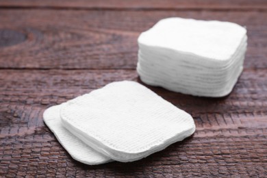 Clean cotton pads on wooden table, closeup