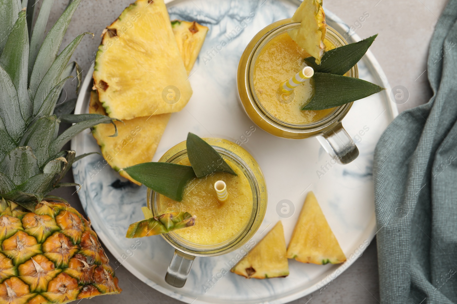 Photo of Tray with tasty pineapple smoothie and sliced fruit on grey table, flat lay