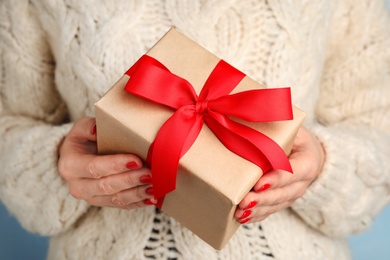 Young woman holding Christmas gift, closeup view