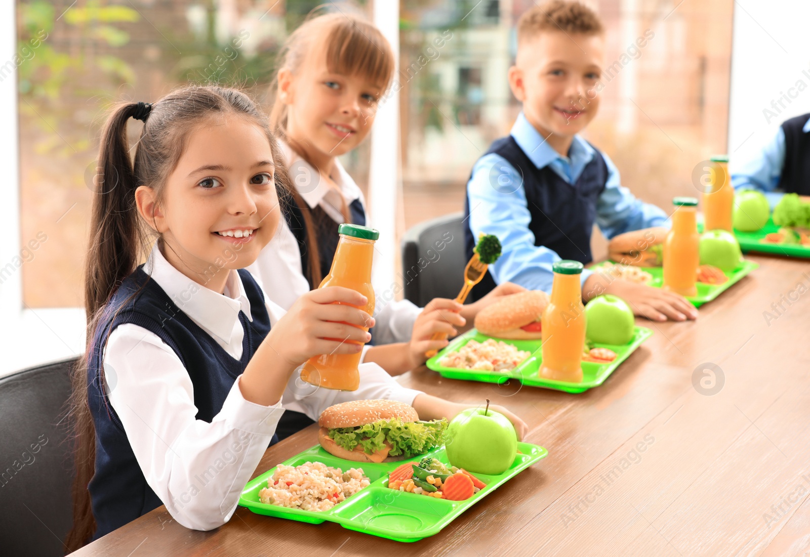 Photo of Happy children at table with healthy food in school canteen