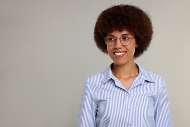 Portrait of happy young woman in eyeglasses on grey background. Space for text