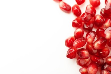 Photo of Many ripe juicy pomegranate grains on white background, flat lay. Space for text