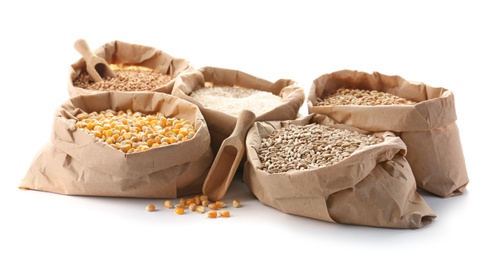 Paper bags with different types of grains and cereals on white background