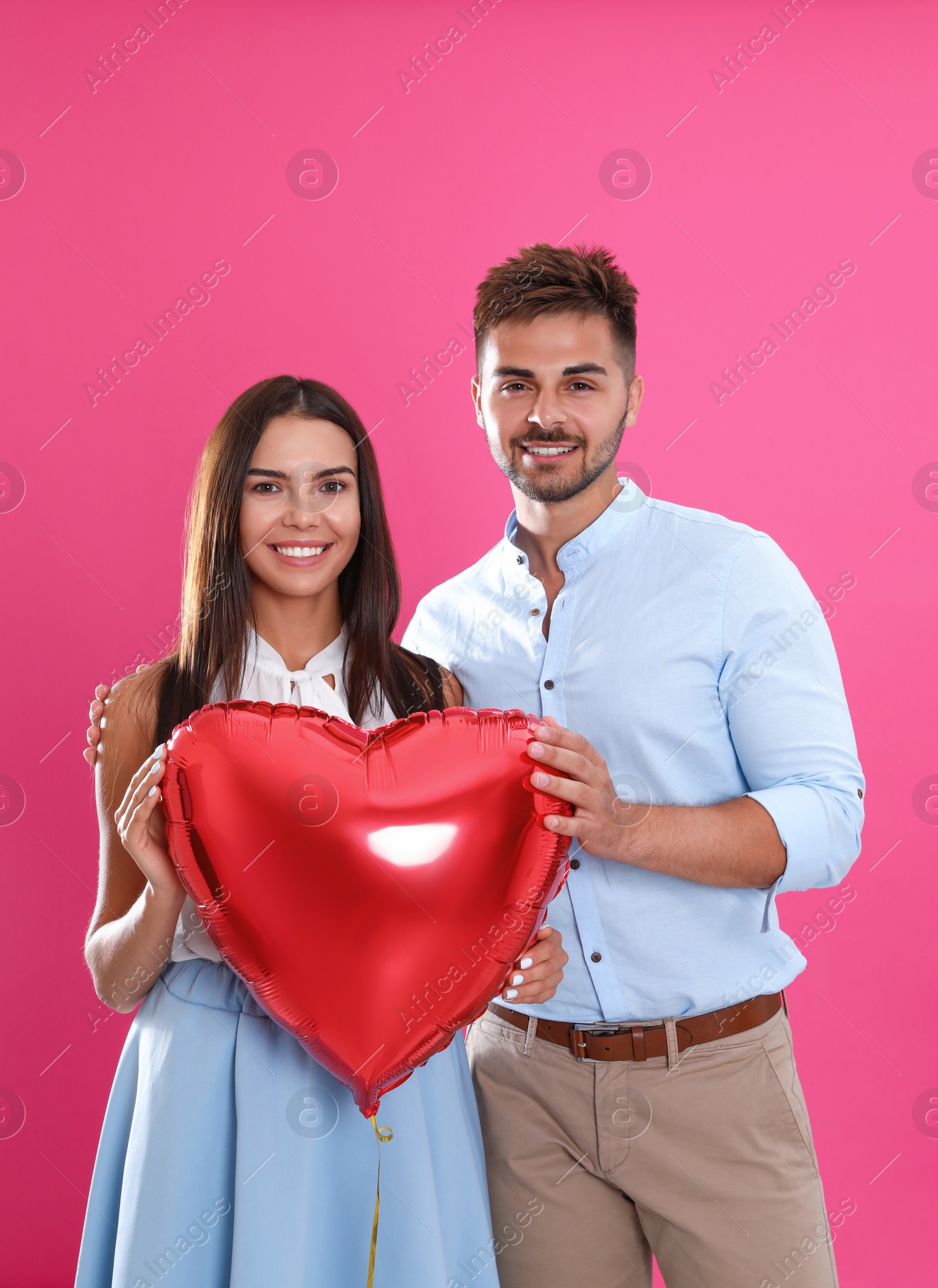 Photo of Young couple with air balloon on pink background. Celebration of Saint Valentine's Day