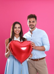 Photo of Young couple with air balloon on pink background. Celebration of Saint Valentine's Day