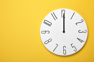 Photo of Modern clock on yellow background, top view. Space for text