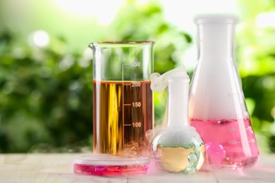 Photo of Laboratory glassware with colorful liquids on wooden table outdoors. Chemical reaction