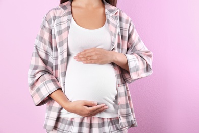 Pregnant woman posing on color background, closeup