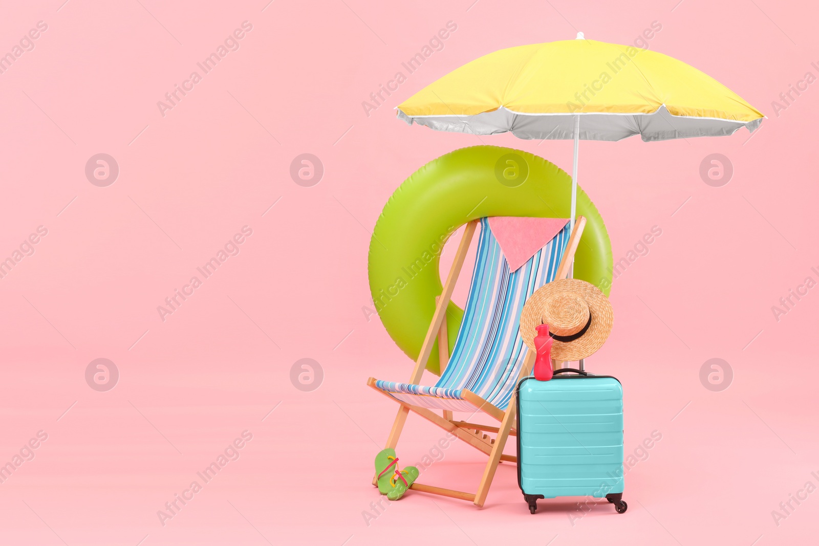 Photo of Deck chair, umbrella, suitcase and beach accessories against pink background, space for text. Summer vacation