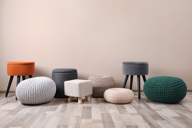 Photo of Different stylish poufs and ottomans near beige wall