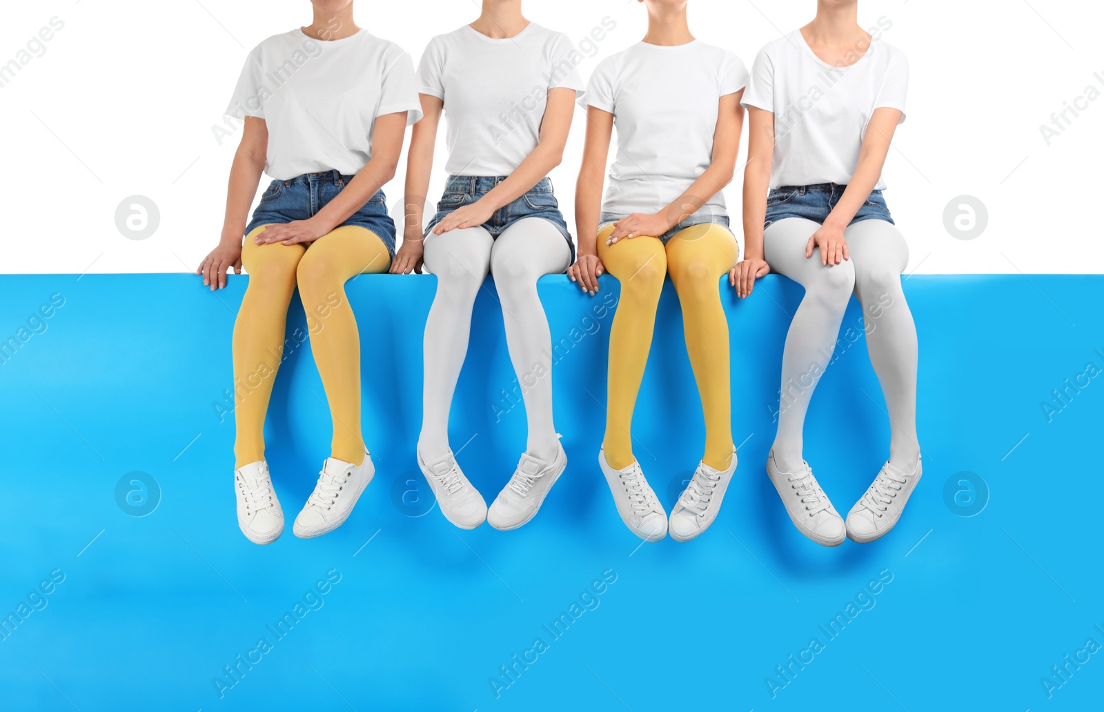 Photo of Group of women wearing colorful tights and stylish shoes sitting on color background, closeup