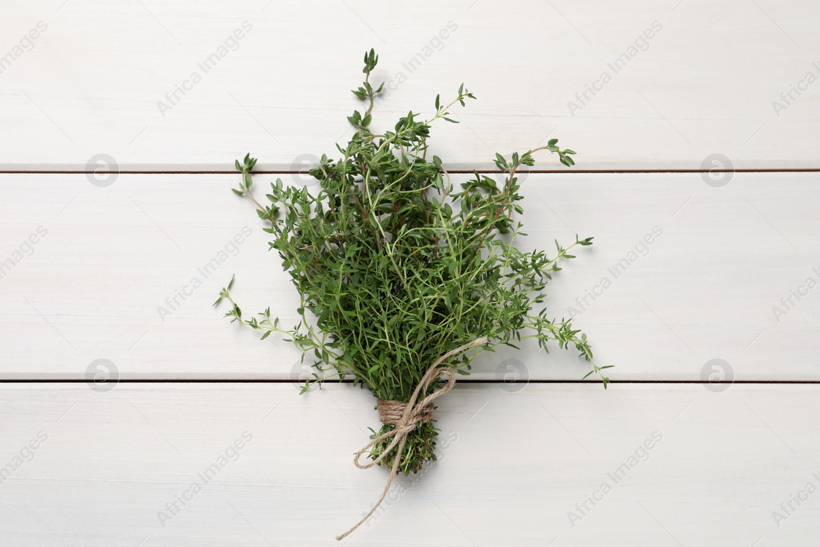 Photo of Bunch of aromatic thyme on white wooden table, top view