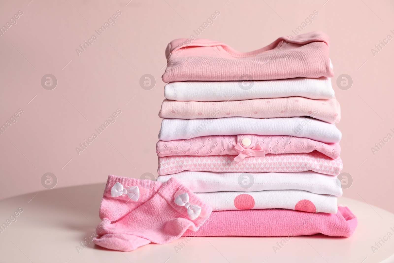 Photo of Stack of clean girl's clothes and socks on table