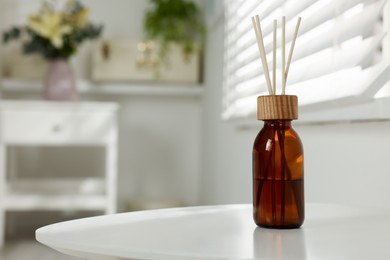 Photo of Aromatic reed air freshener on white table in room. Space for text