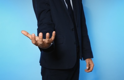 Businessman holding something on color background, closeup of hands