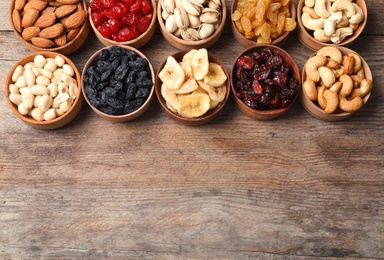 Composition of different dried fruits and nuts on wooden background, top view. Space for text