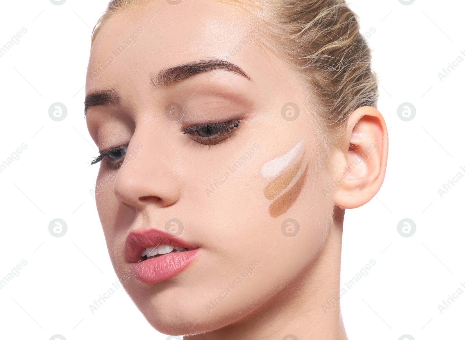 Photo of Young woman with different shades of skin foundation on her face against white background. Professional makeup