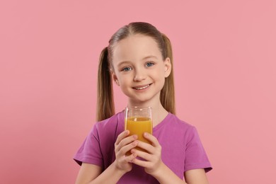 Cute little girl with glass of fresh juice on pink background