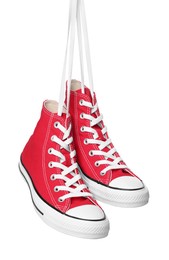 Pair of new red stylish high top plimsolls hanging on white background