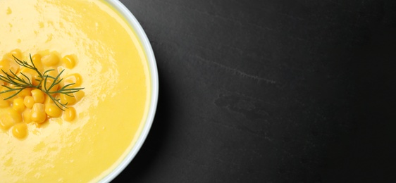 Photo of Delicious creamy corn soup on black table, top view