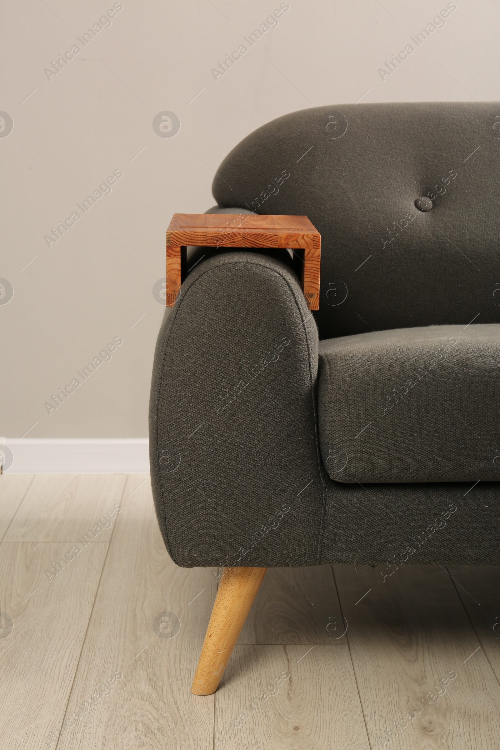 Photo of Wooden armrest table on sofa in room. Interior element