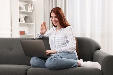 Happy woman with laptop having video chat in room