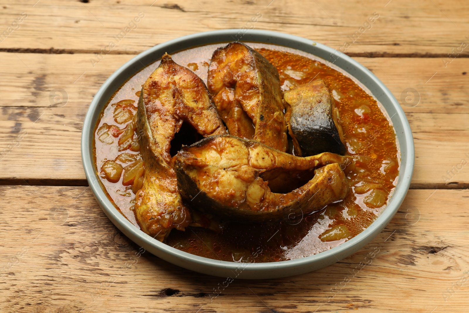 Photo of Tasty fish curry on wooden table, closeup. Indian cuisine