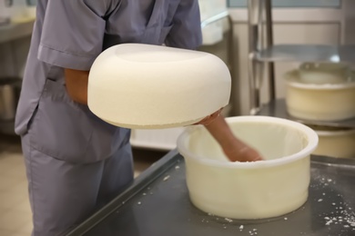 Photo of Worker holding fresh cheese at modern factory, closeup