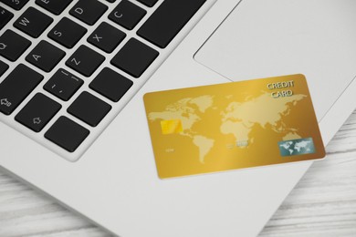 Online payment concept. Bank card with laptop on white wooden table, closeup