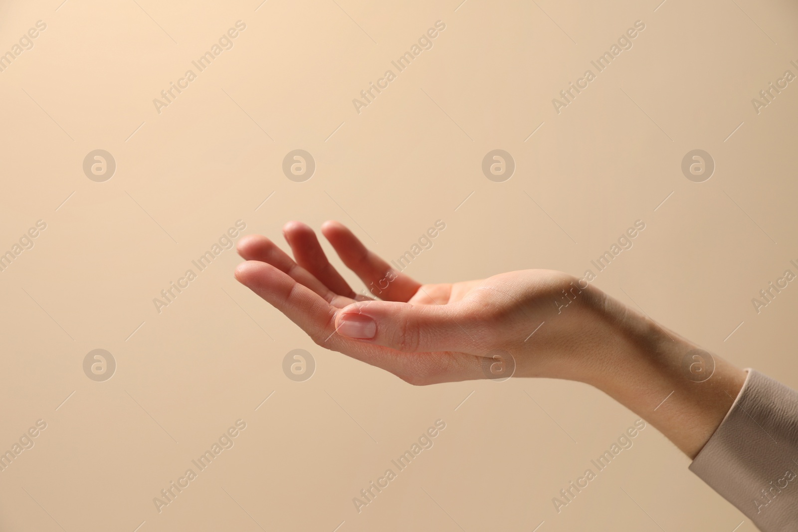 Photo of Woman holding something in hand on beige background, closeup