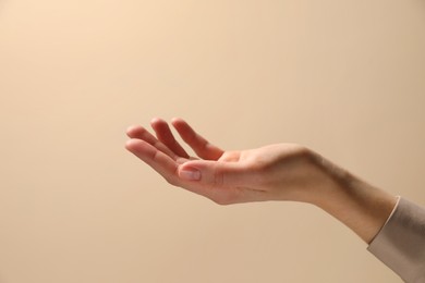 Woman holding something in hand on beige background, closeup