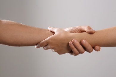 Photo of Man and woman holding hands on grey background, closeup. Help and support concept