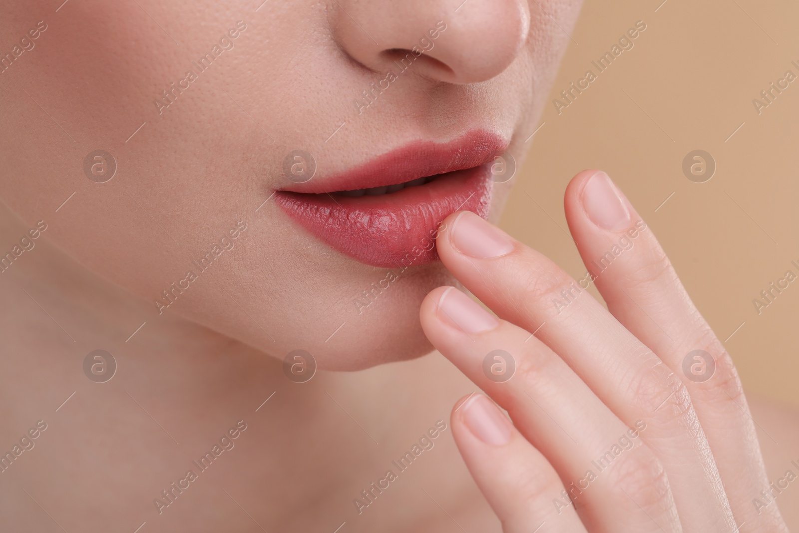 Photo of Young woman with beautiful full lips on beige background, closeup