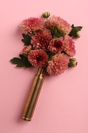 Beautiful flowers in bullet case on pink background, top view