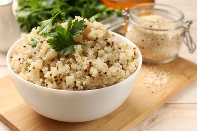 Photo of Tasty quinoa porridge with parsley in bowl on light table, closeup. Space for text