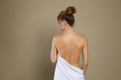 Photo of Back view of woman with perfect smooth skin on beige background. Beauty and body care