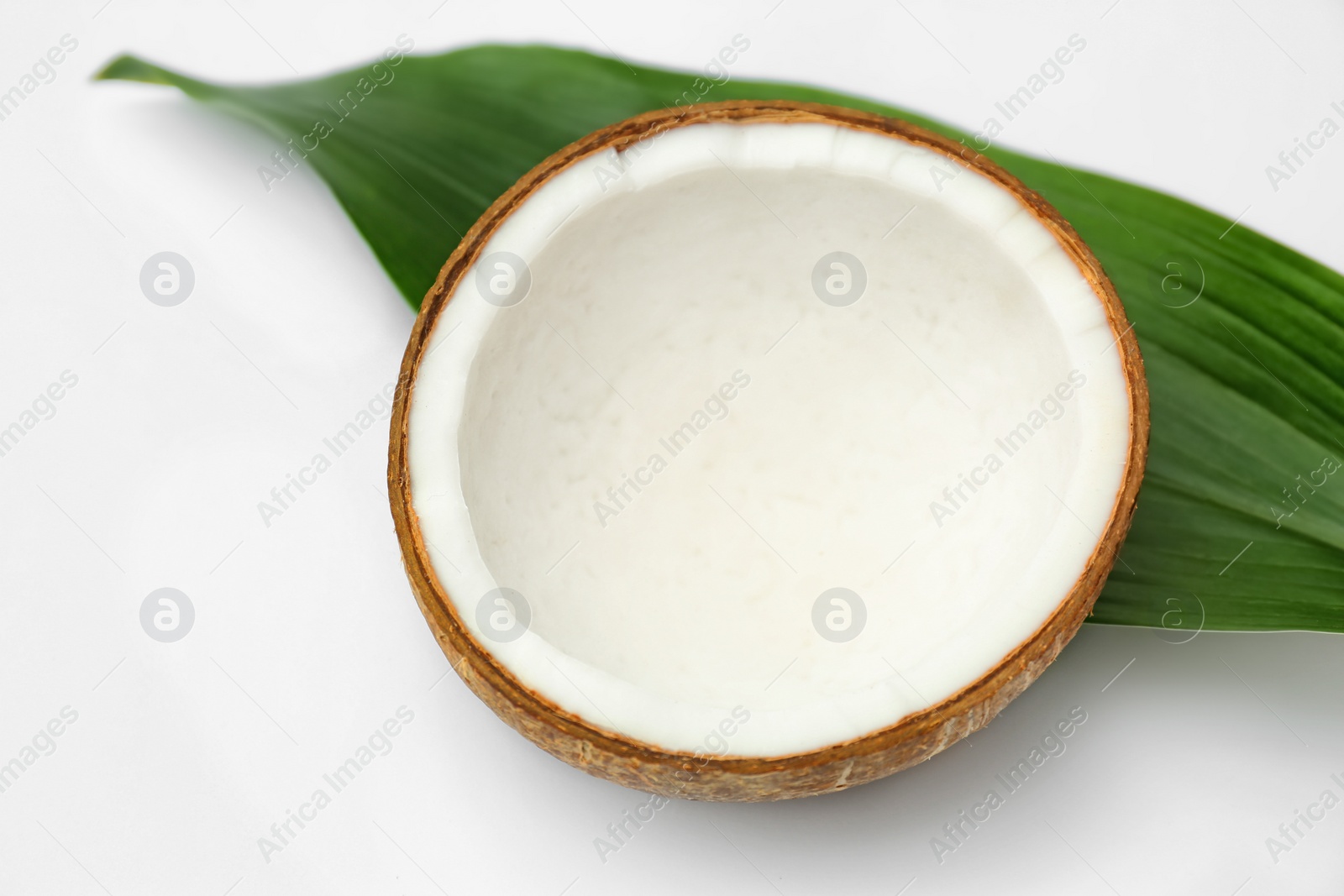 Photo of Half of fresh coconut and palm leaf on white background