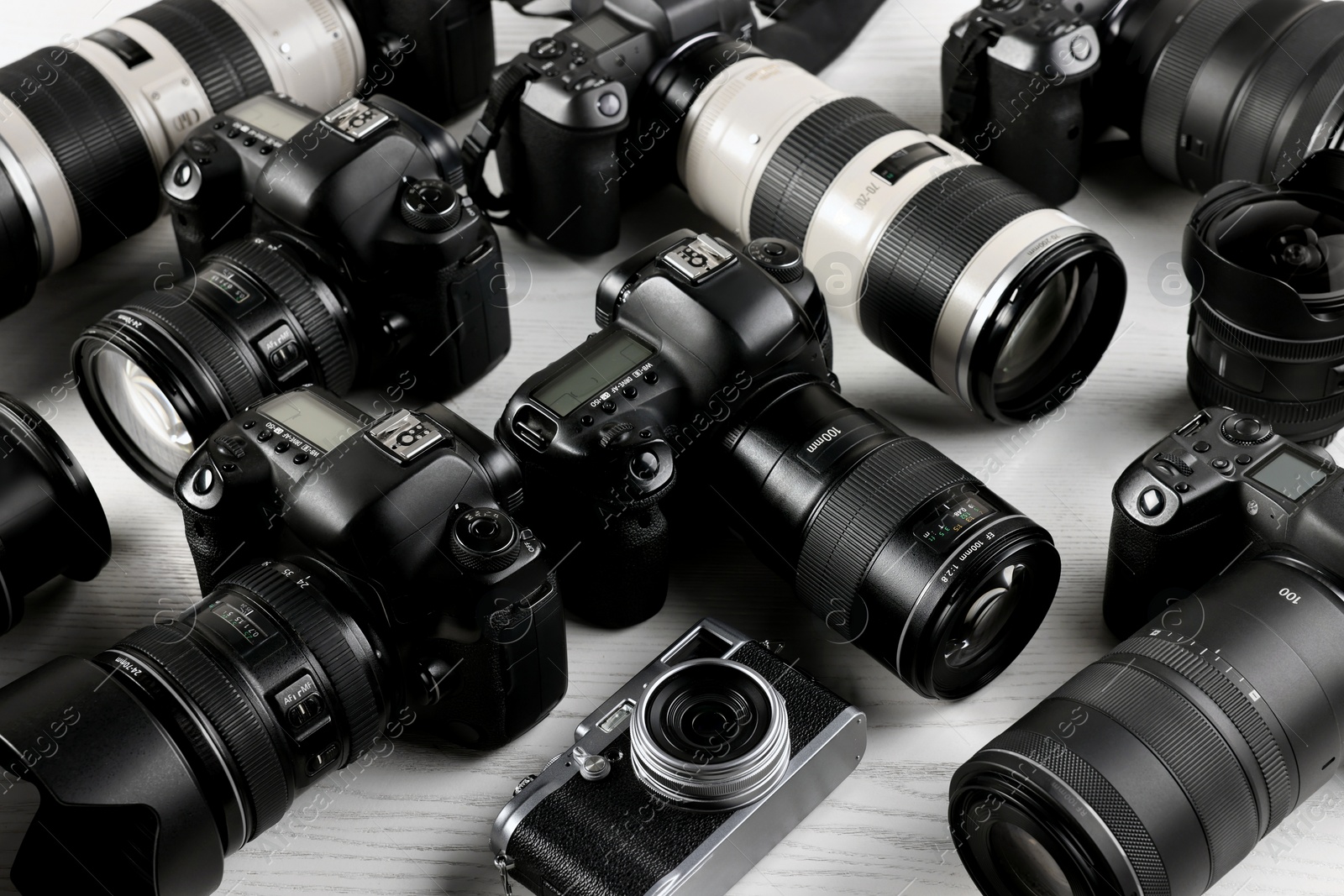 Photo of Modern cameras on white wooden table, closeup