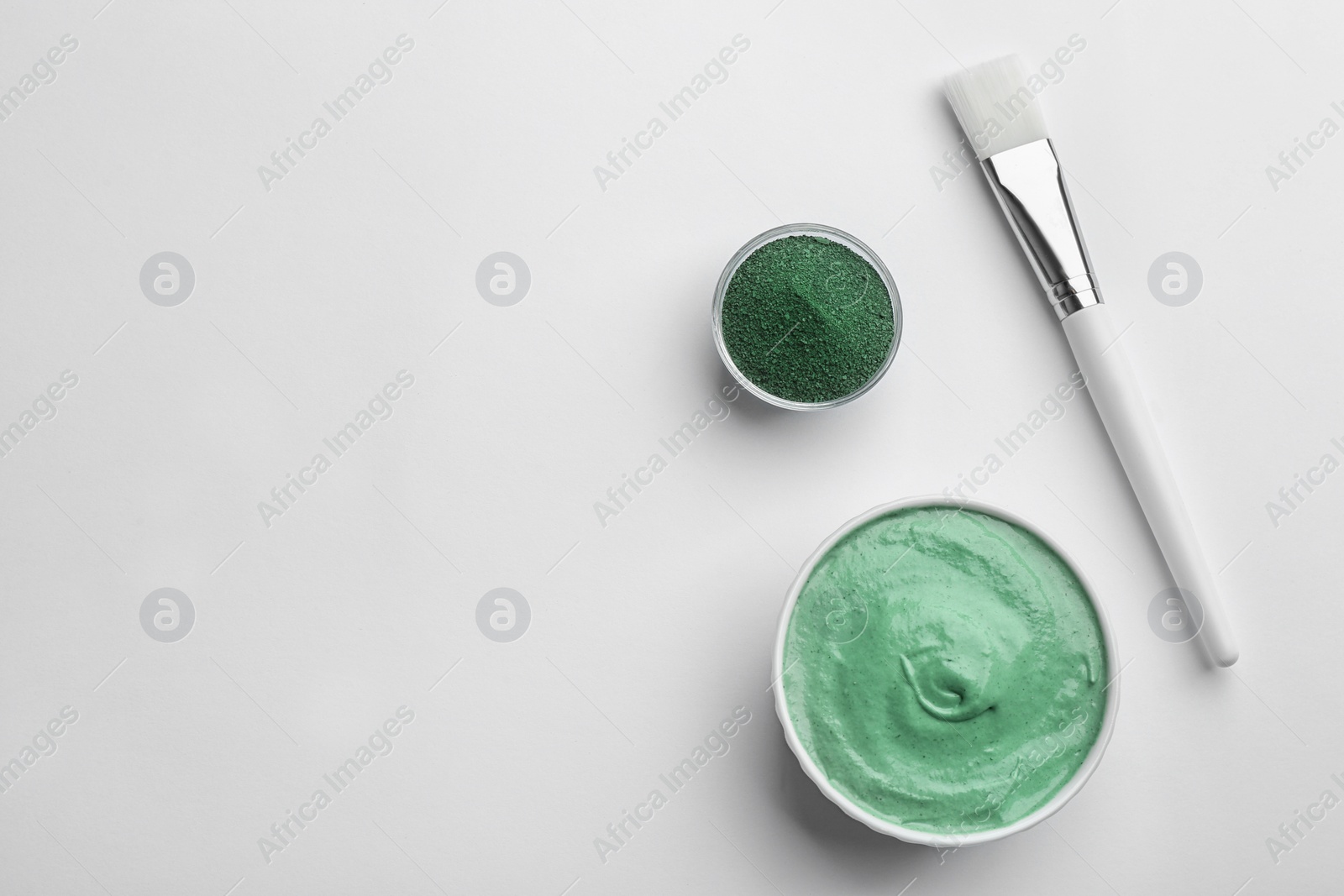 Photo of Spirulina facial mask, brush and powder on white background, top view