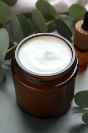 Jar of hand cream and eucalyptus branches on plate, closeup